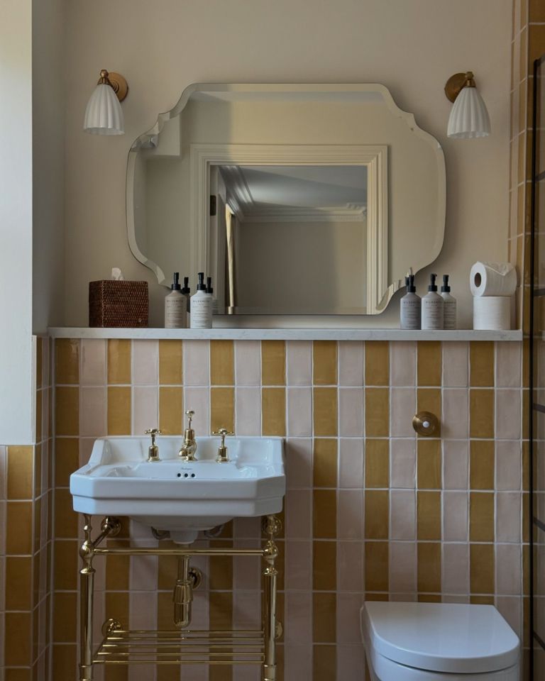 a bathroom with pink and gold tiles and a sink