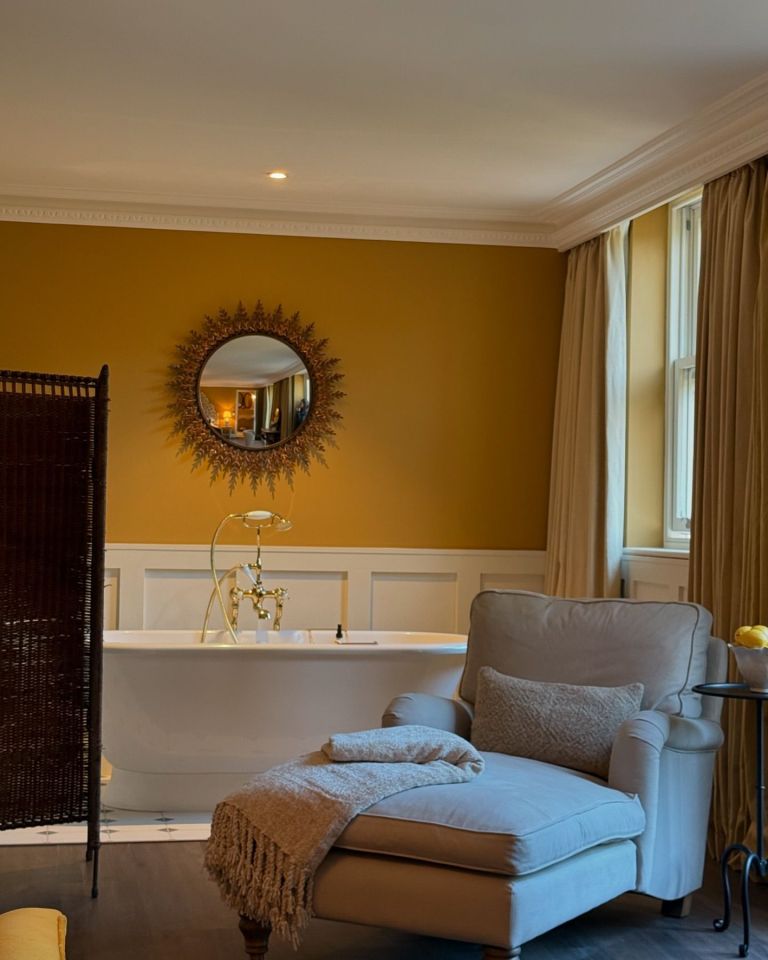 a chair sits in front of a bathtub in a bathroom