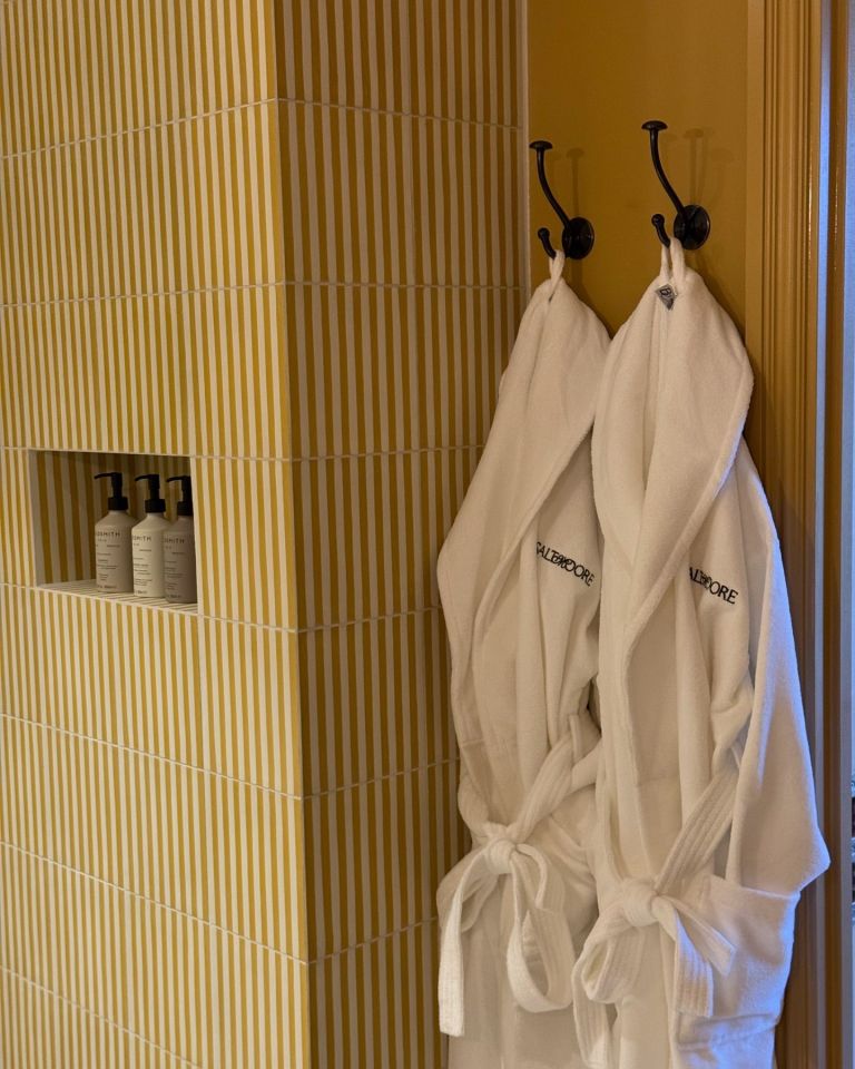 two bathrobes with baltimore embroidered on them hang on hooks