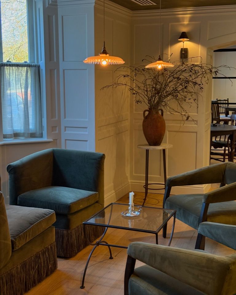 a living room with chairs and a table with a candle on it