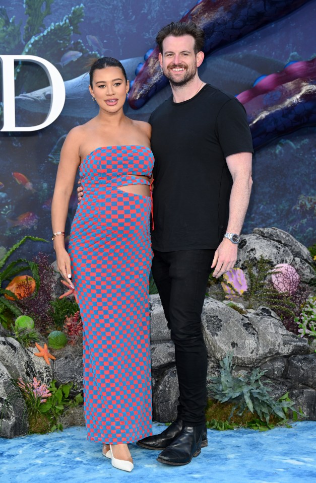 a man and a woman pose for a picture on a blue carpet