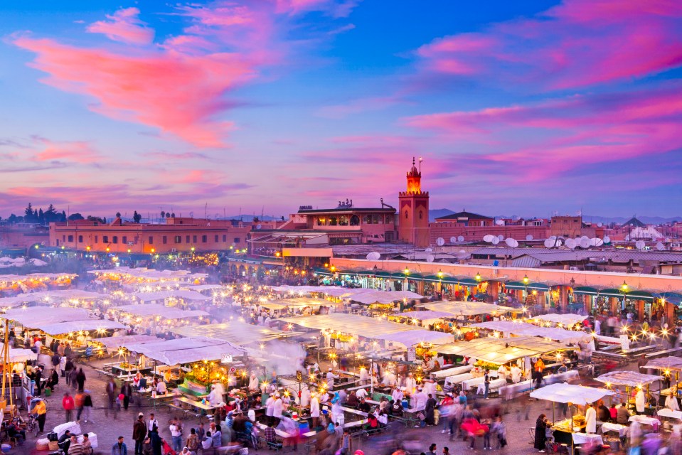 a crowded market with a pink sky in the background