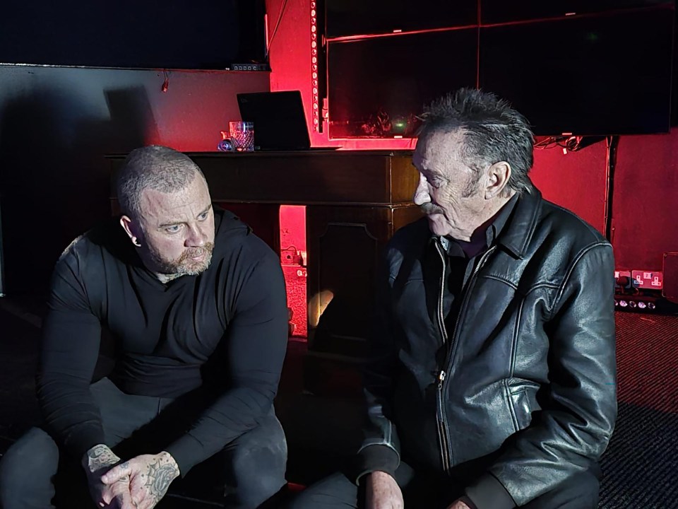 a man in a leather jacket sits next to another man