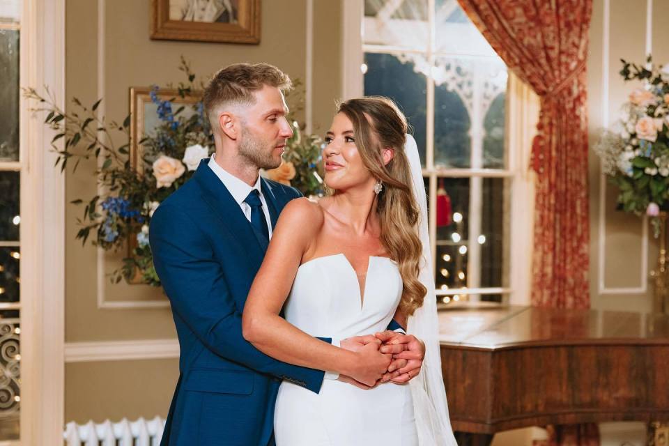 a bride and groom pose for a picture in front of a piano