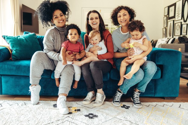 a group of women are sitting on a blue couch holding babies