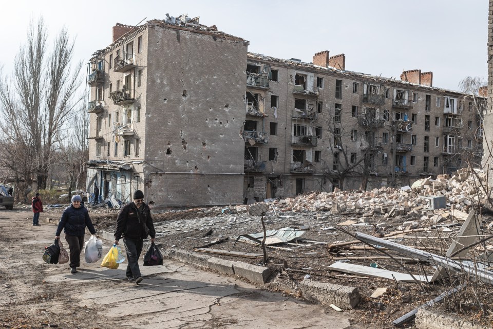 Neighbors carry belongings out of their damaged homes after a Russian attack in Kostiantynivka, Ukraine