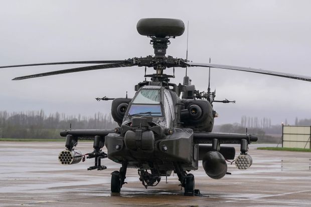 a military helicopter is parked on a wet runway