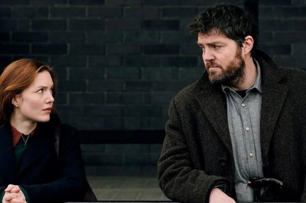 a man and a woman are looking at each other in front of a brick wall