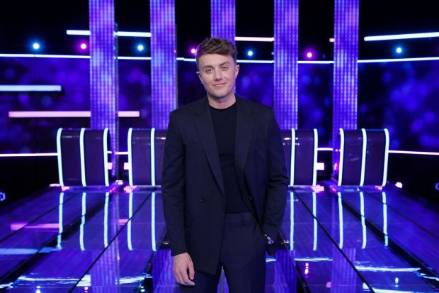 a man in a suit stands in front of purple lights