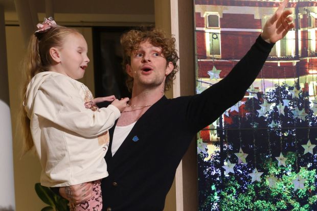 a man with curly hair is holding a little girl in his arms