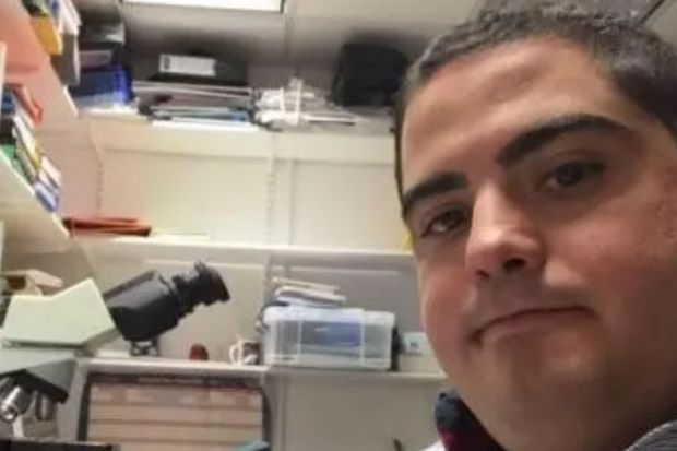 a man is taking a selfie in a lab with a microscope in the background .