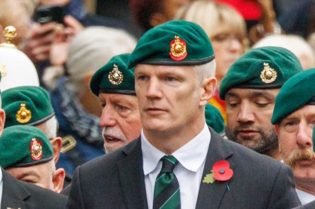 a man wearing a green beret with a gold emblem on it