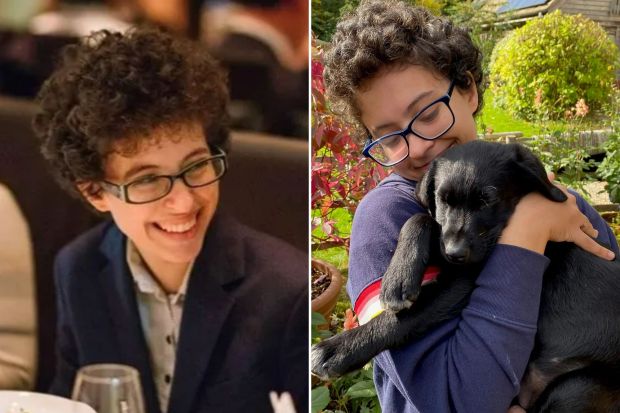 a boy with curly hair and glasses holds a black dog