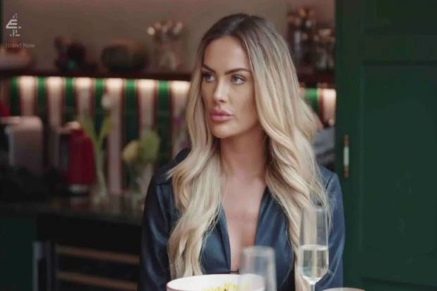 a woman is sitting at a table with a bowl of food and a glass of wine .