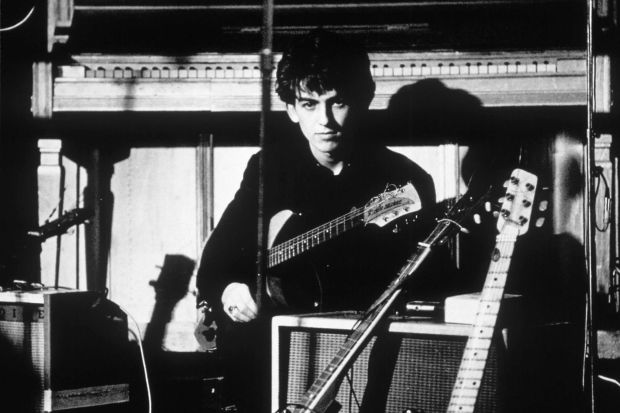 a black and white photo of a man playing a rickenbacker guitar