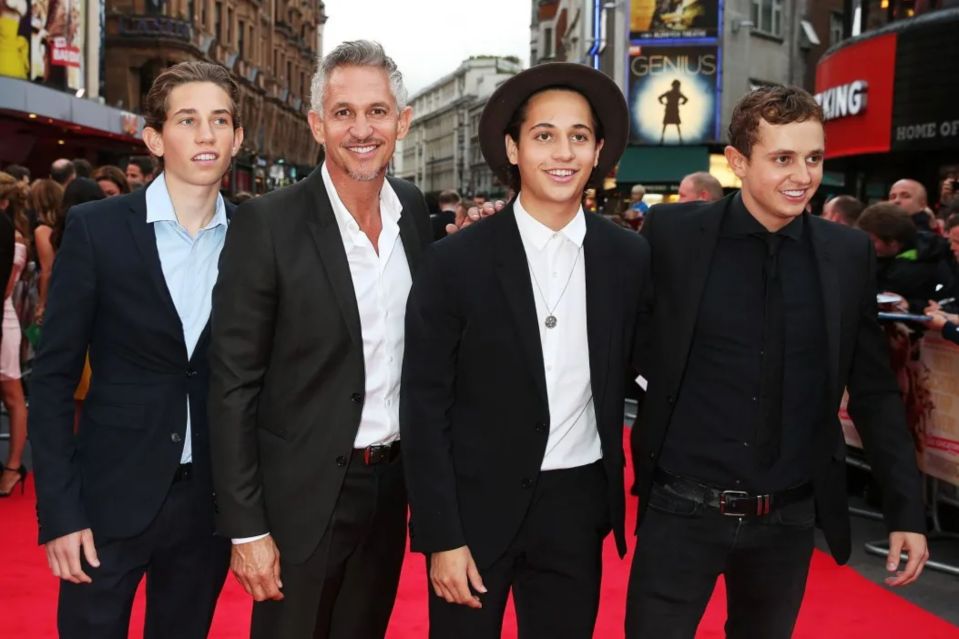 a group of men standing on a red carpet in front of a sign that says genius