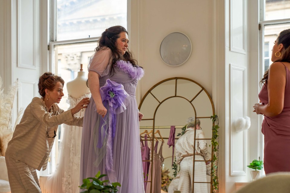 a woman in a purple dress is being helped by another woman