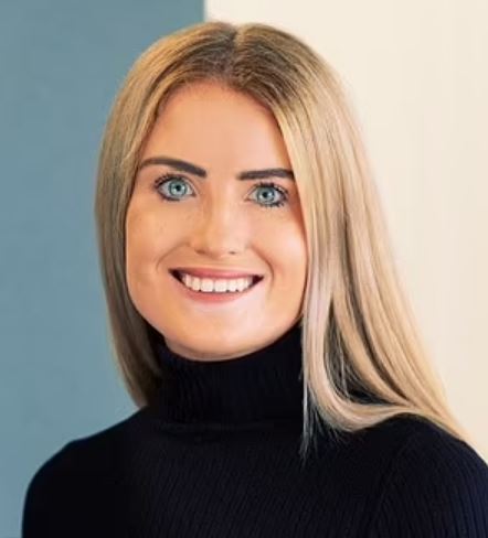 the woman is wearing a black turtleneck and smiling for the camera .