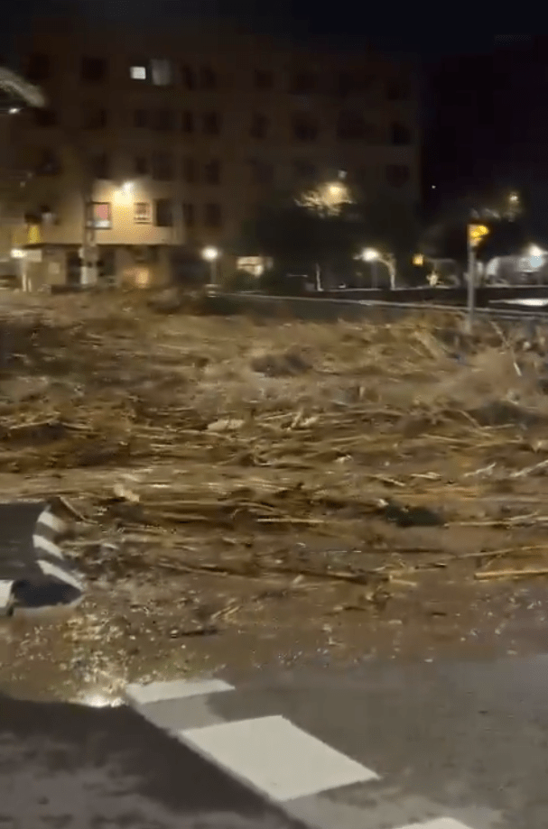 a flooded street at night with a building in the background