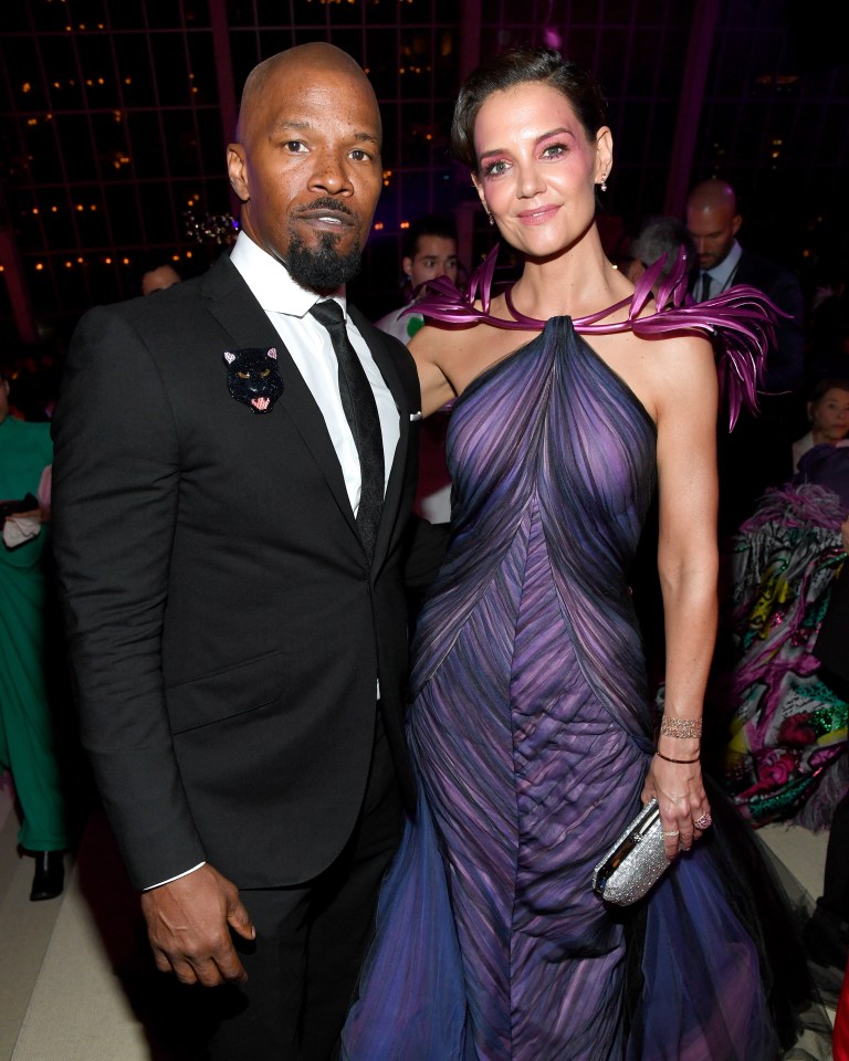 a man in a suit and tie stands next to a woman in a purple dress