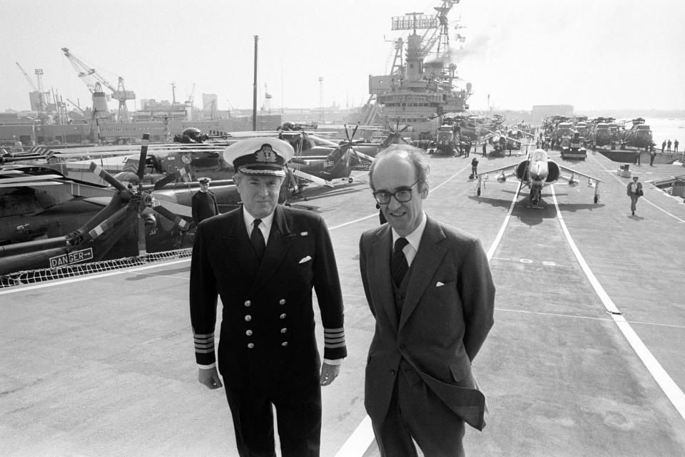 two men standing in front of a large ship with a license plate that says jdn 632