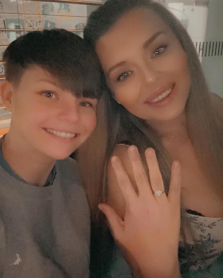 a woman shows off her engagement ring next to a boy