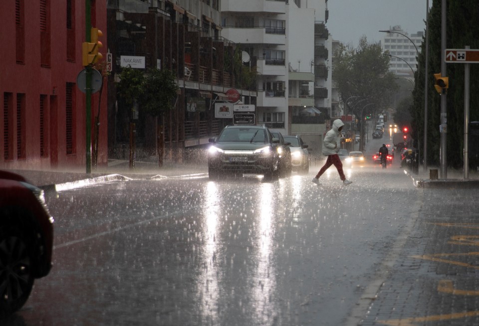 a car with a license plate that starts with a s is driving down a street in the rain