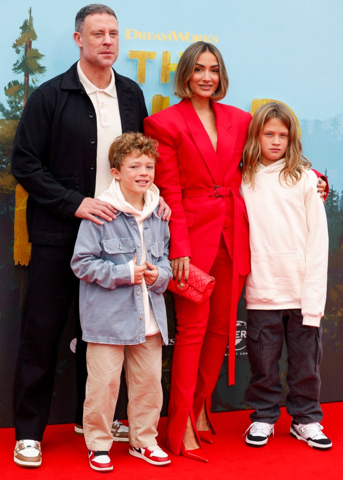 a family poses on a red carpet in front of a dreamworks sign