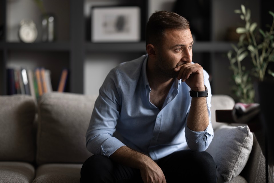 a man sitting on a couch with his hand on his chin