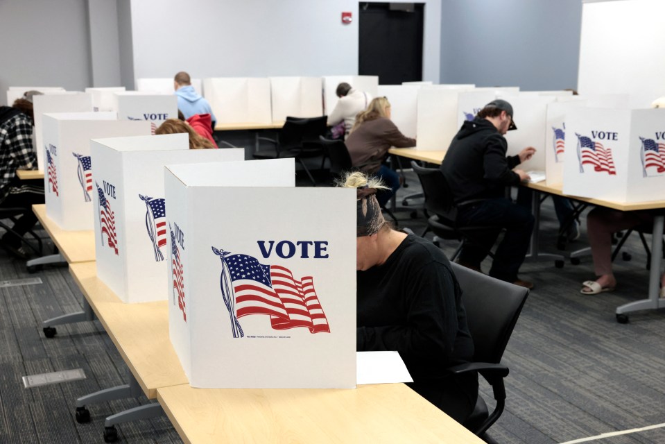 a woman sits at a table with a sign that says vote