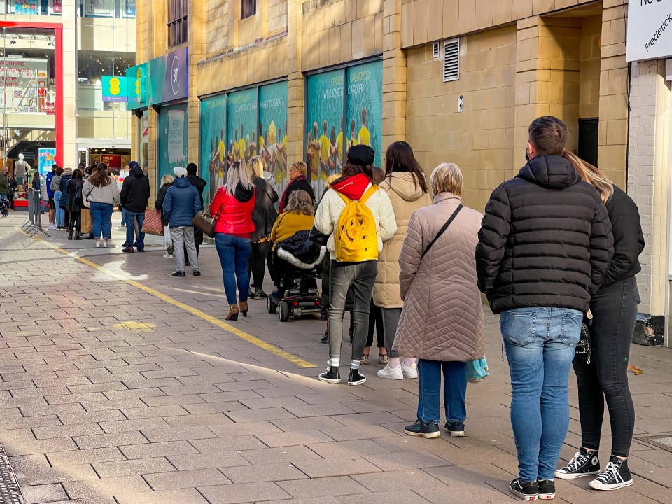 a line of people waiting in front of a store that says tesco