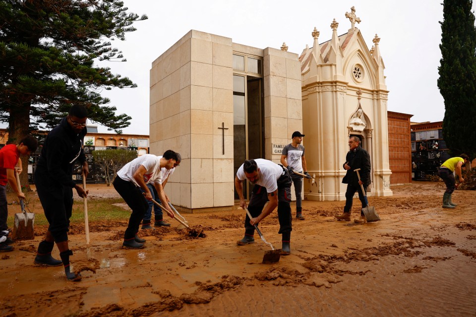 People remove mud at a cemetery on All Saints’ Day