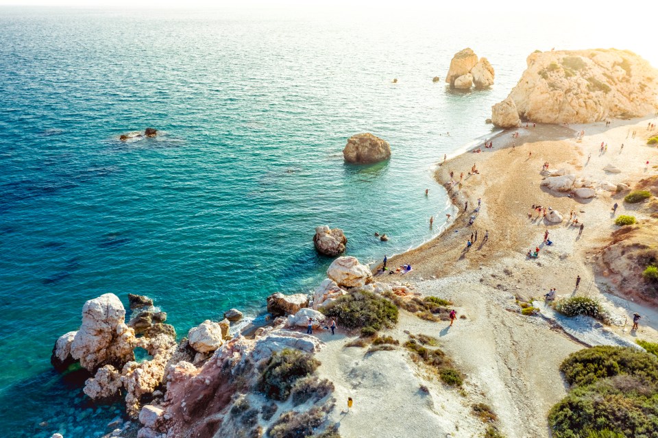 a group of people are walking on a beach near the ocean