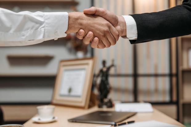 a man in a suit shakes hands with another man in a white shirt