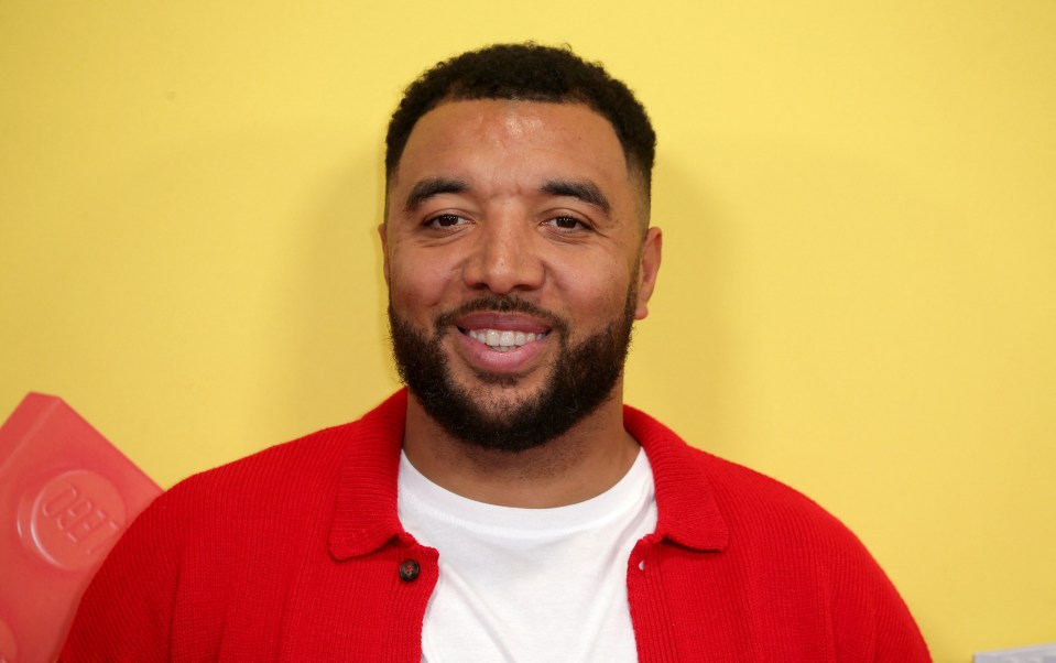 a man with a beard wears a red sweater and a white shirt