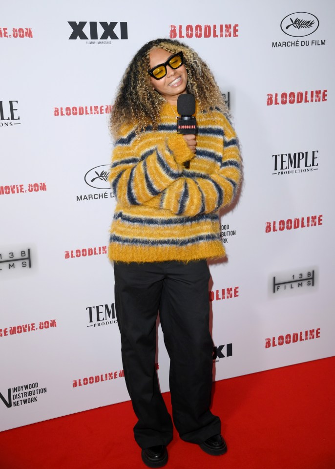 a woman holding a microphone on a red carpet that says bloodline