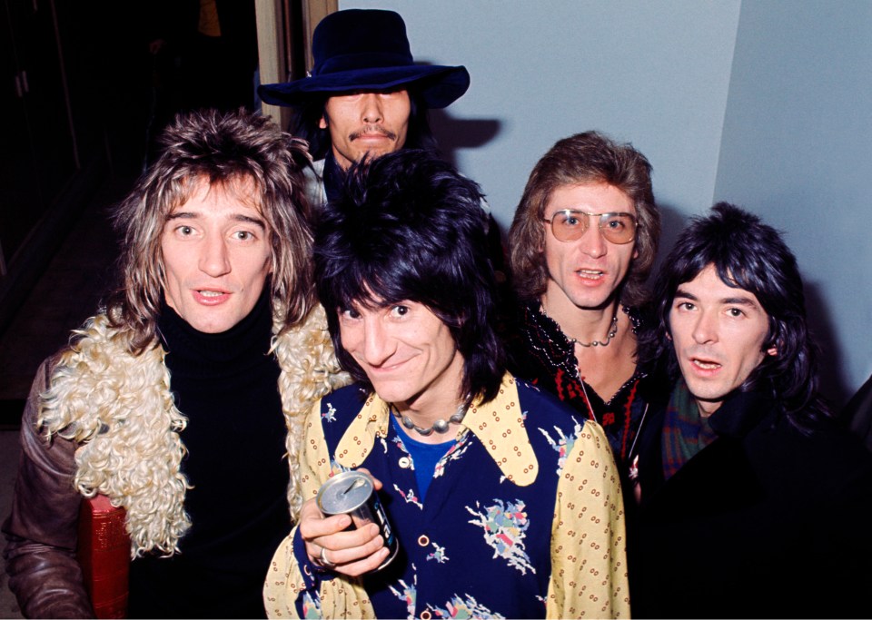 a group of men are posing for a picture and one of them is holding a can of soda