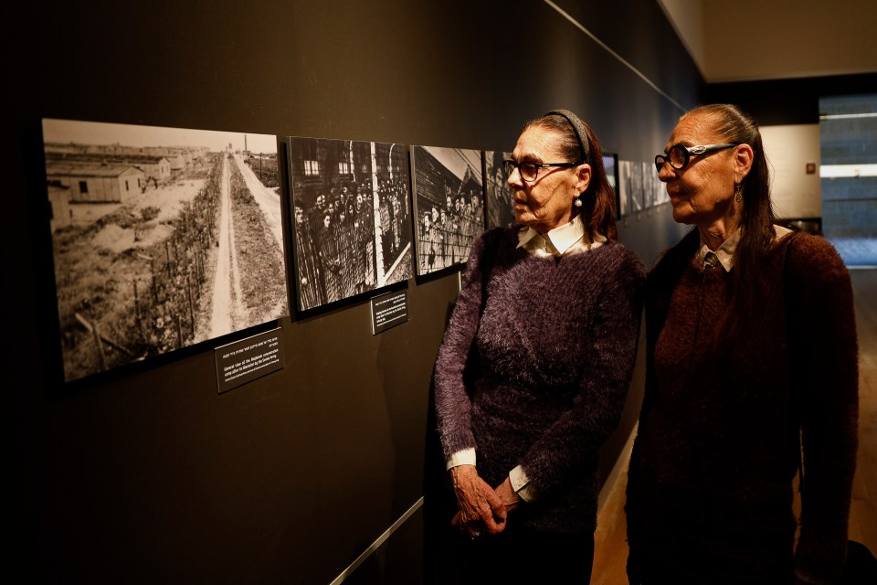 two women are looking at a display of photographs on a wall