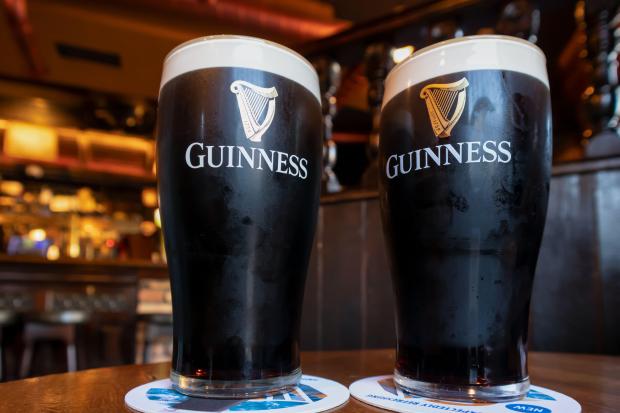 two glasses of guinness sit on a coaster on a table