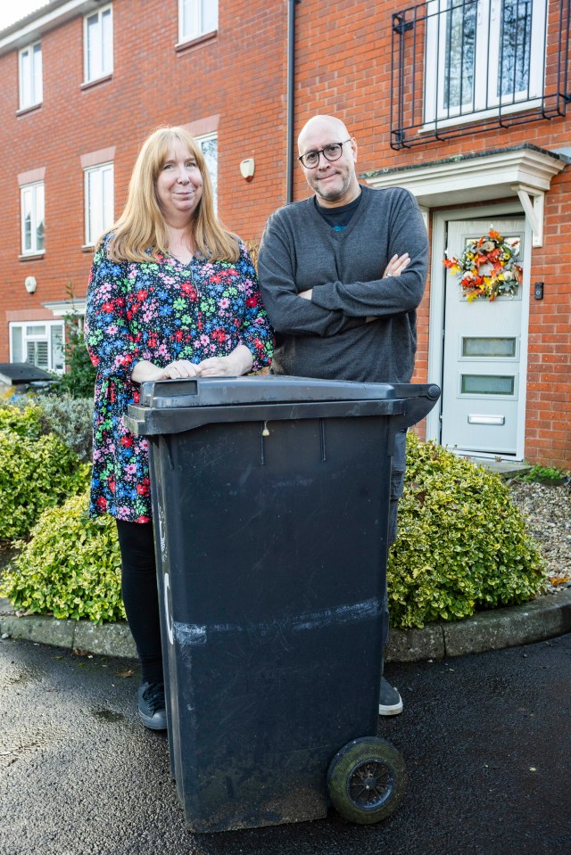 a man and a woman standing next to a trash can