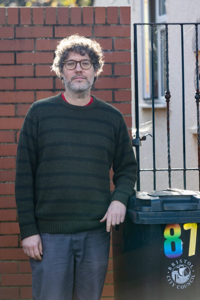 a man standing next to a trash can that says bristol city council