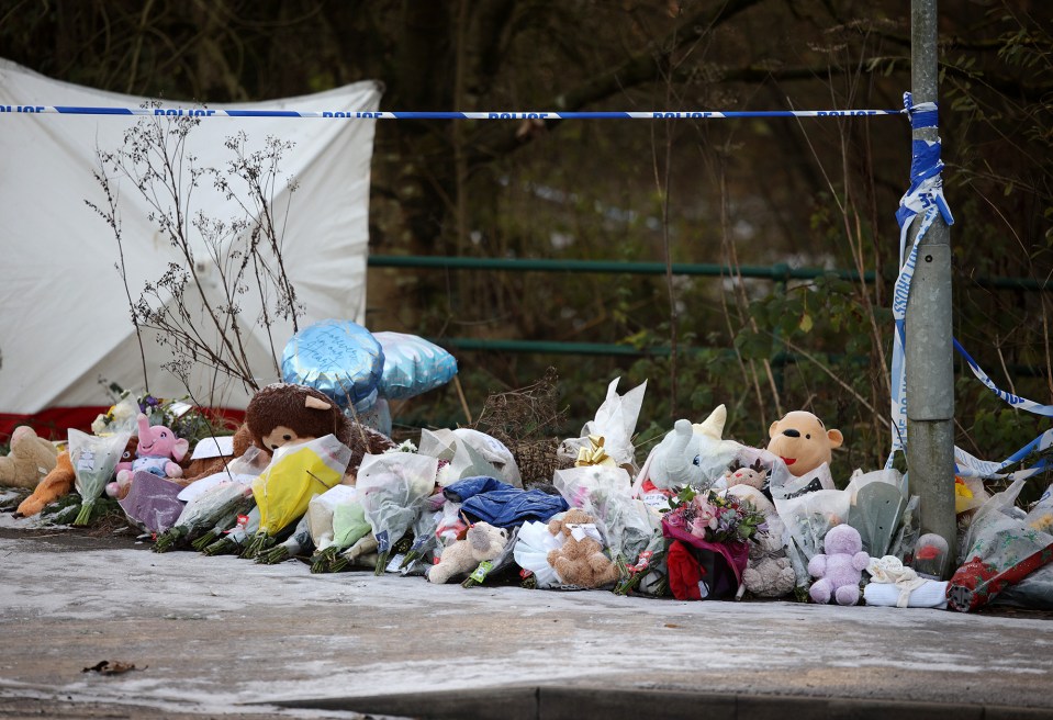 stuffed animals and flowers are lined up in front of a police tape