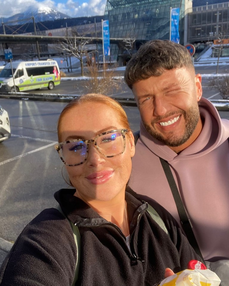 a man and woman are posing for a picture in front of an airport transport van