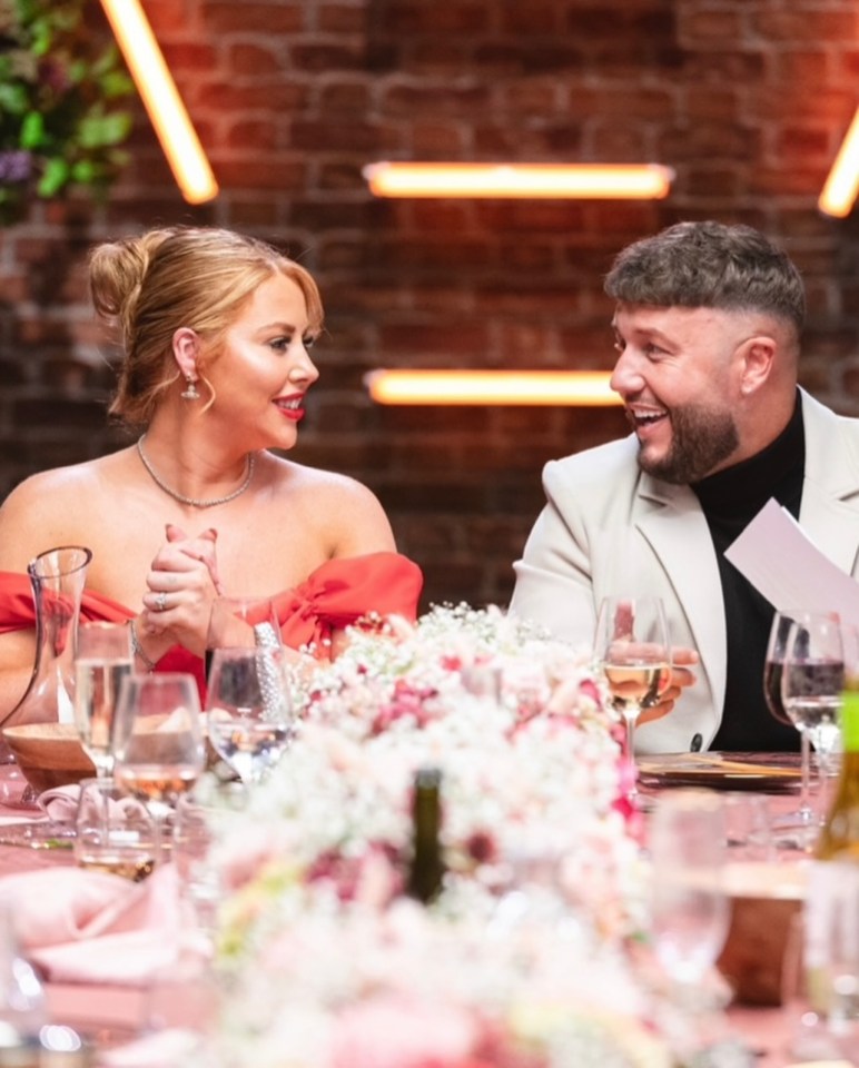 a man and a woman are sitting at a table with wine glasses and flowers