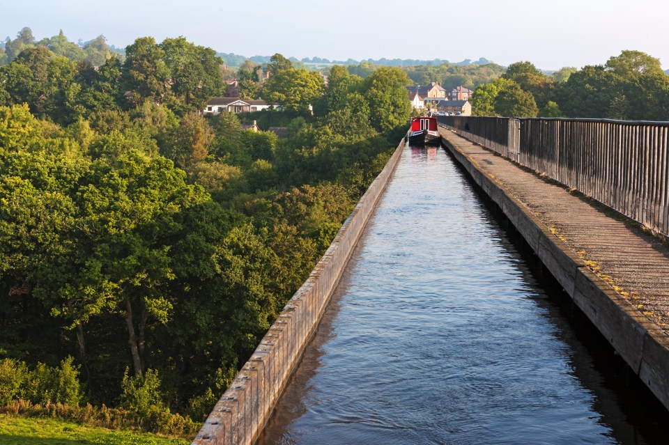 a red boat is going down a river on a bridge