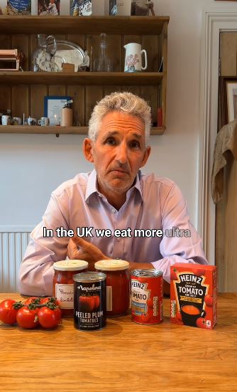 a man is sitting at a table with jars of tomatoes and ketchup .