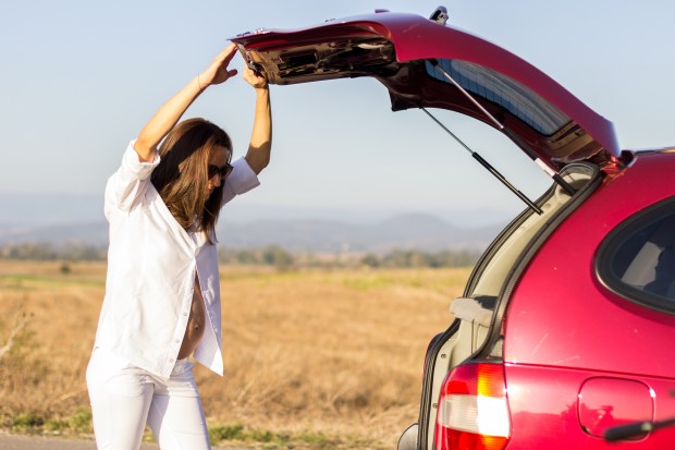 a woman standing next to a red car with the trunk open