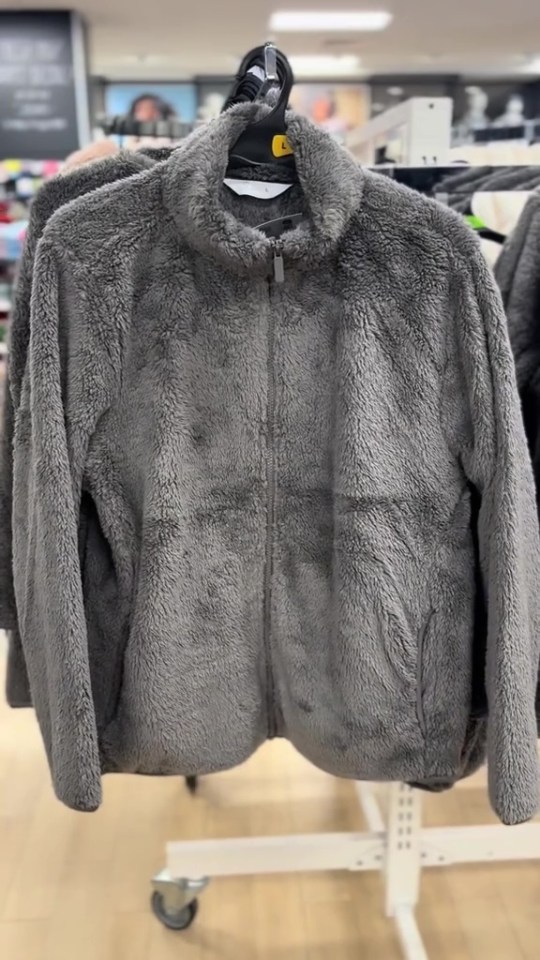 a grey jacket is hanging on a rack in a store