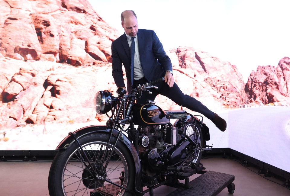 a man in a suit is standing on a motorcycle that says triumph