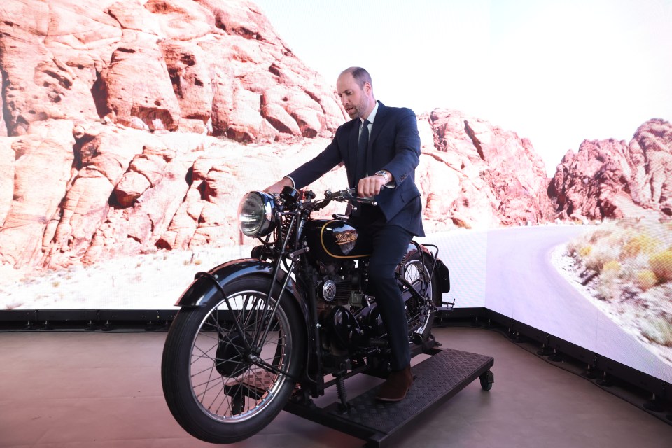 a man in a suit sits on a triumph motorcycle